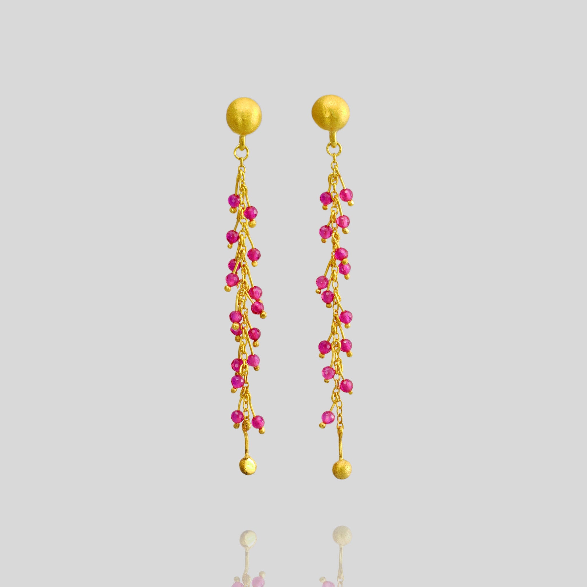 Close up of 18k gold studs adorned with radiant ruby beads on shimmering gold threads, inspired by Venus emerging from the sea.