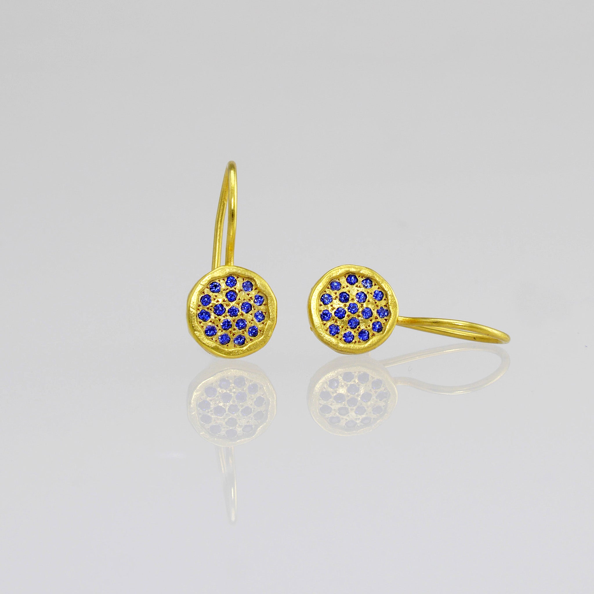 Close up of Gold drop earrings adorned with twinkling Sapphires, reminiscent of a starry night sky.