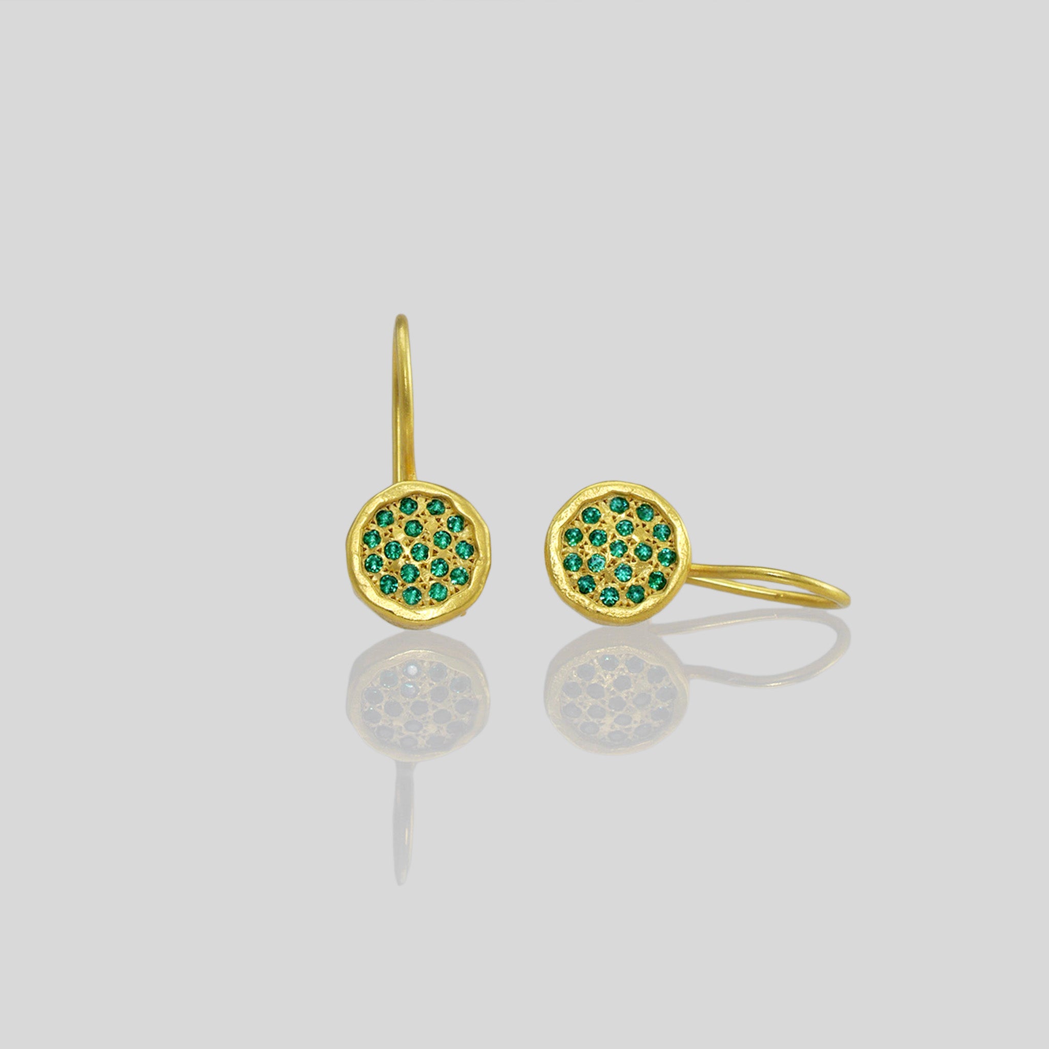 Close up of Gold drop earrings adorned with twinkling Emerald gemstones, reminiscent of a starry night sky.