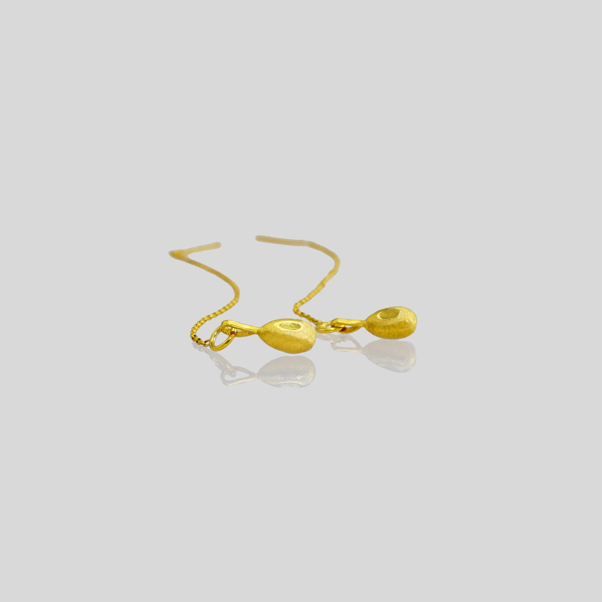 Nature-inspired gold earrings with a delicate chain and needle-tip attachment, embodying graceful and organic movement.