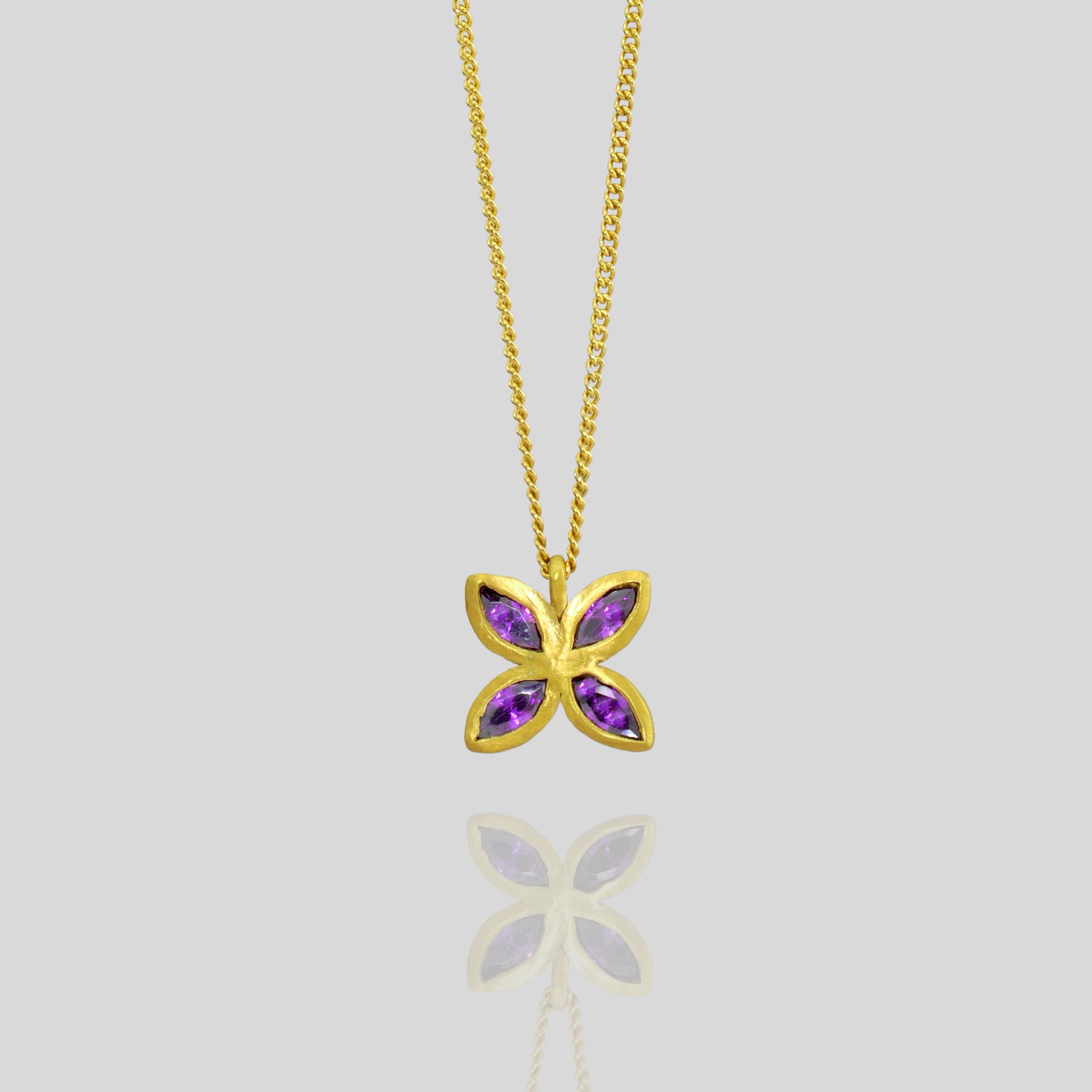 close up of an Elegant gold pendant with four marquise-cut amethysts arranged into a delicate flower design, offering luxury and beauty suitable for any gift occasion.