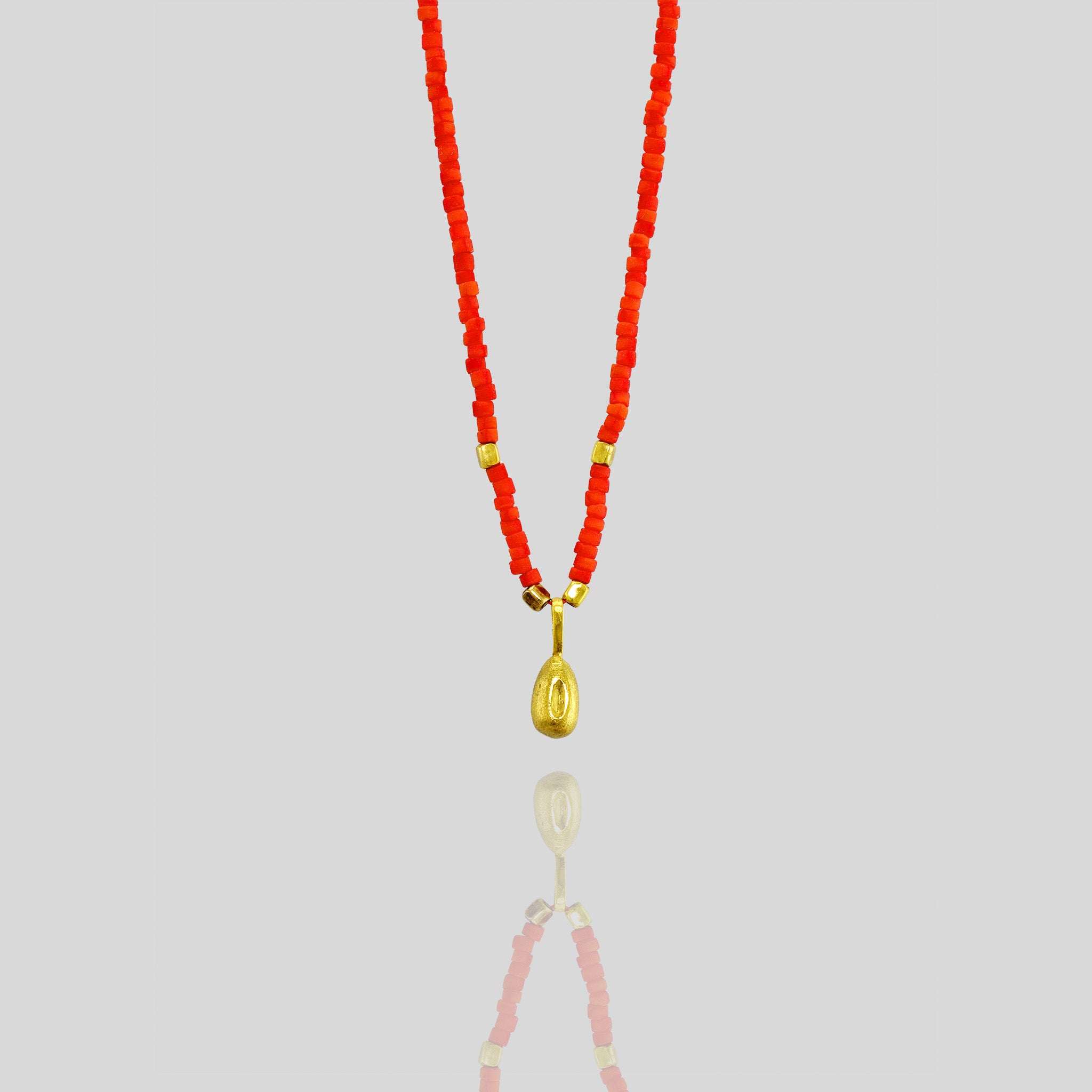 Playful and elegant Koral necklace with a natural gold seed charm, adding a colorful and mischievous touch to any outfit.