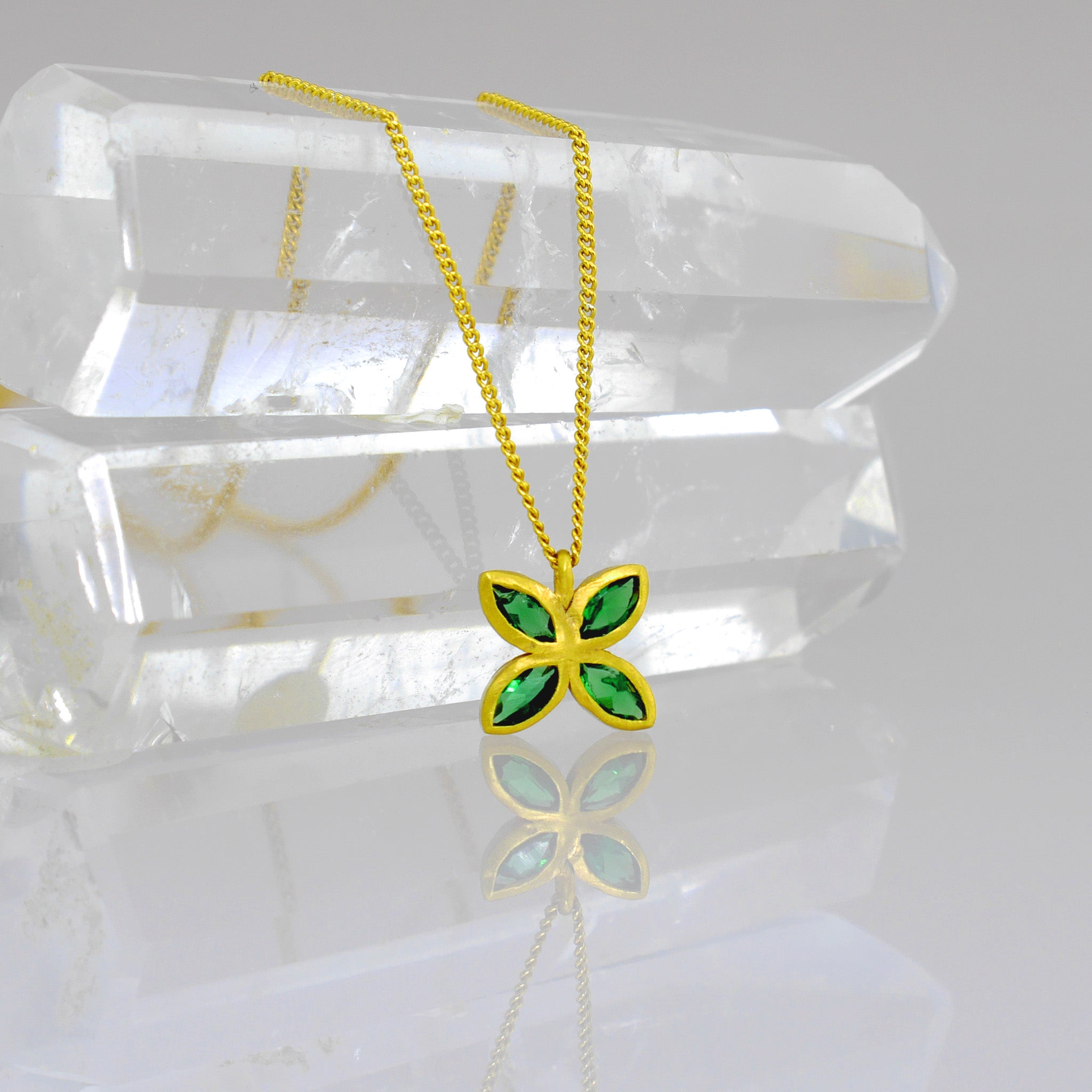 Close up of an Elegant gold pendant with four marquise-cut Emeralds arranged into a delicate flower design, offering luxury and beauty suitable for any gift occasion.