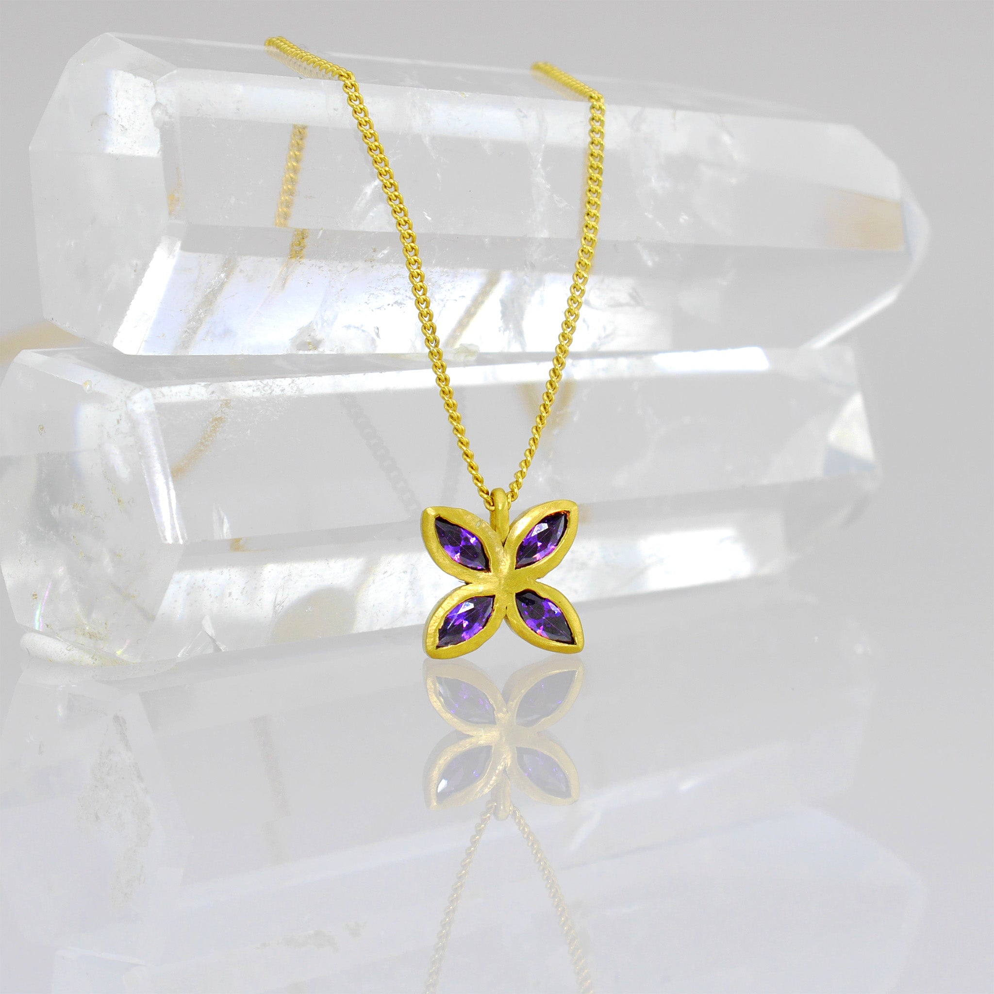 close up of an Elegant gold pendant with four marquise-cut amethysts arranged into a delicate flower design, offering luxury and beauty suitable for any gift occasion.