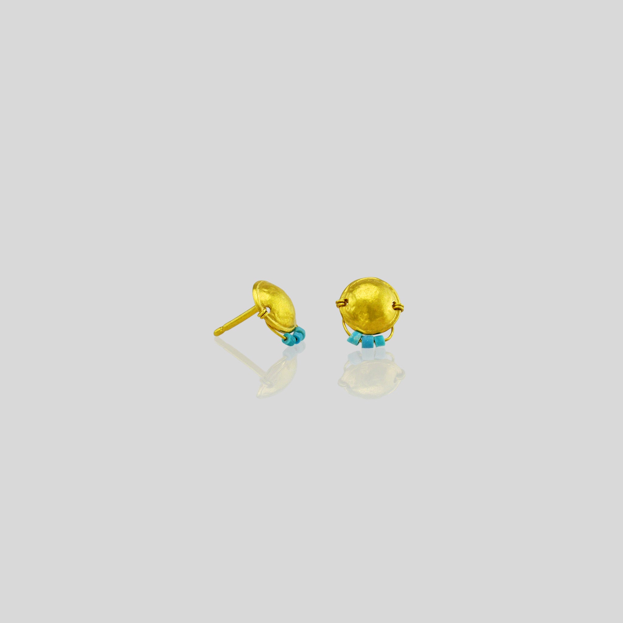 Handmade gold stud earrings featuring an arched disk adorned with a golden thread and tiny turquoise beads hanging on a golden bow. 