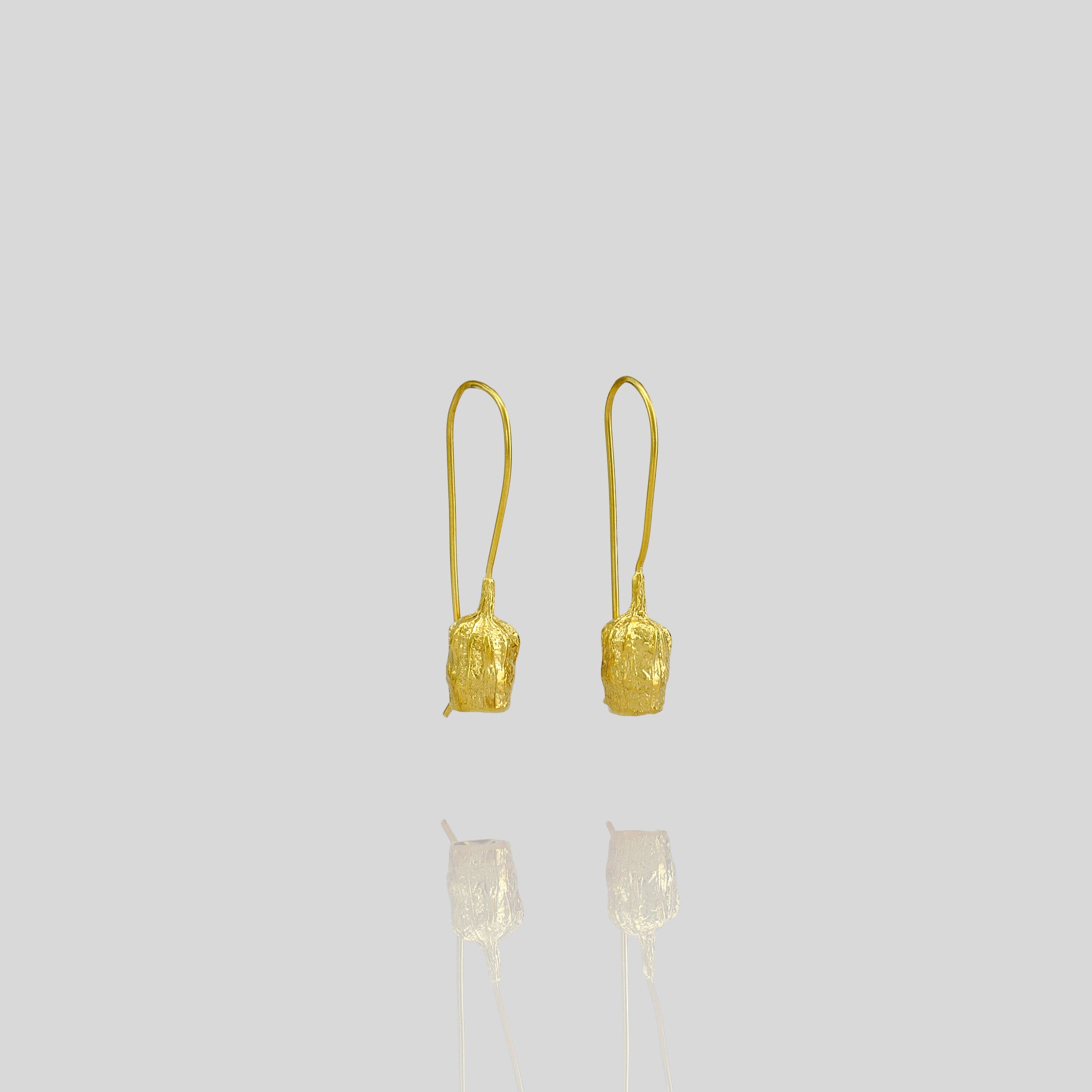Gold drop earrings featuring a bell-shaped seed, which is a replica of a dried seed collected from nature.