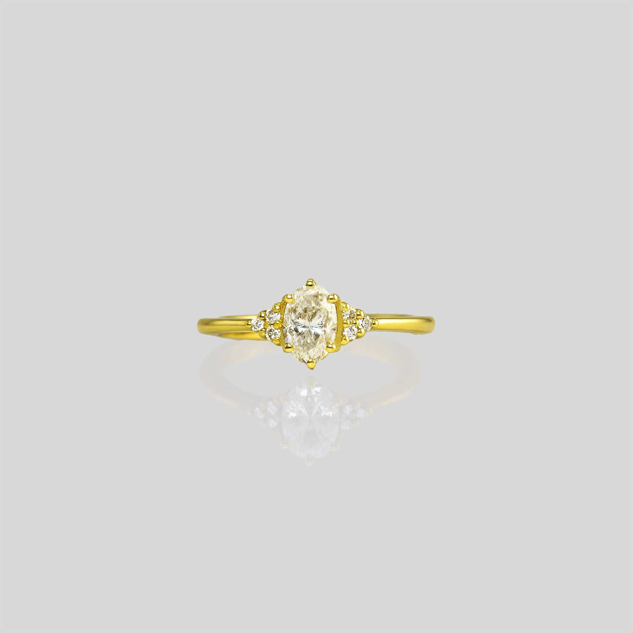 Front look of our timeless Classic Gold Engagement Ring. Delicately designed with an oval diamond surrounded by six smaller diamonds, it exudes elegance and charm, symbolizing everlasting love.