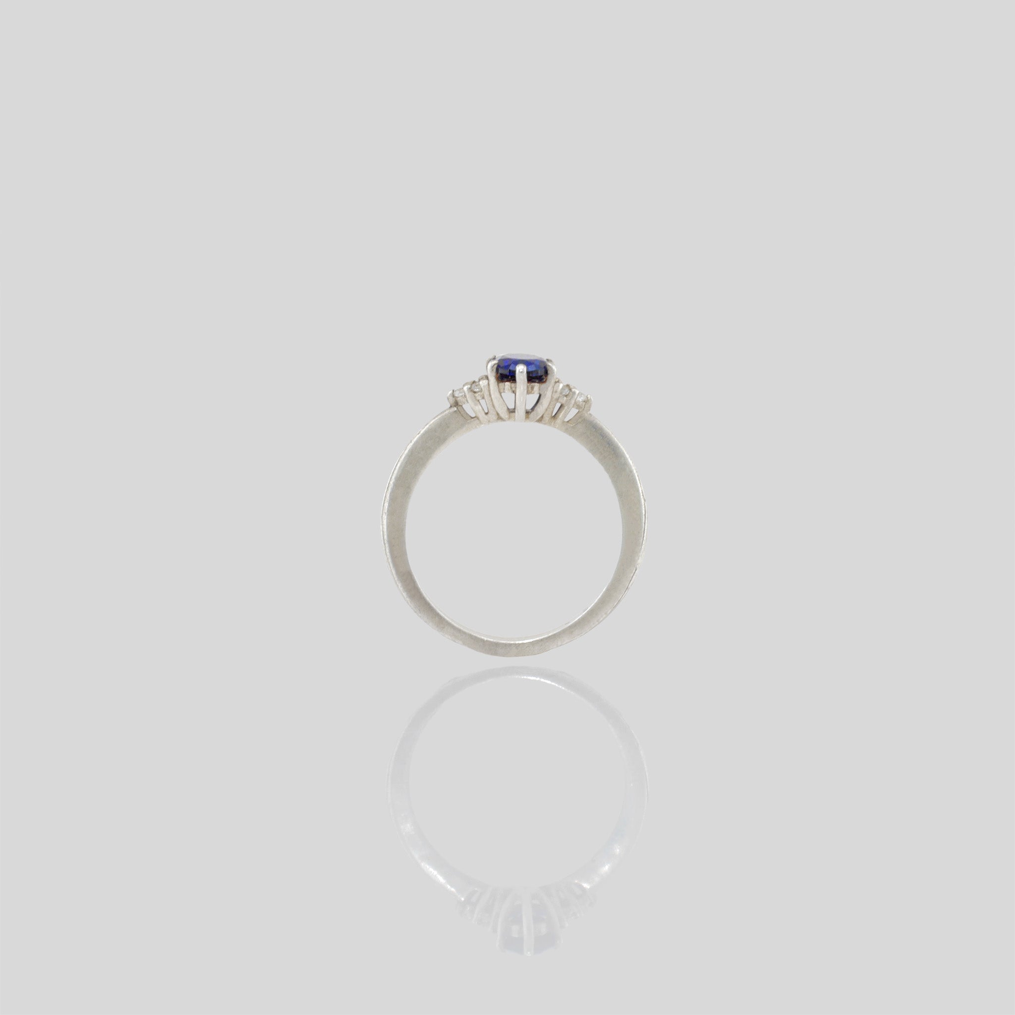 Side view of our White Gold engagement ring featuring an oval central Sapphire and three dainty Diamonds on each side, offering timeless elegance with added sparkle.