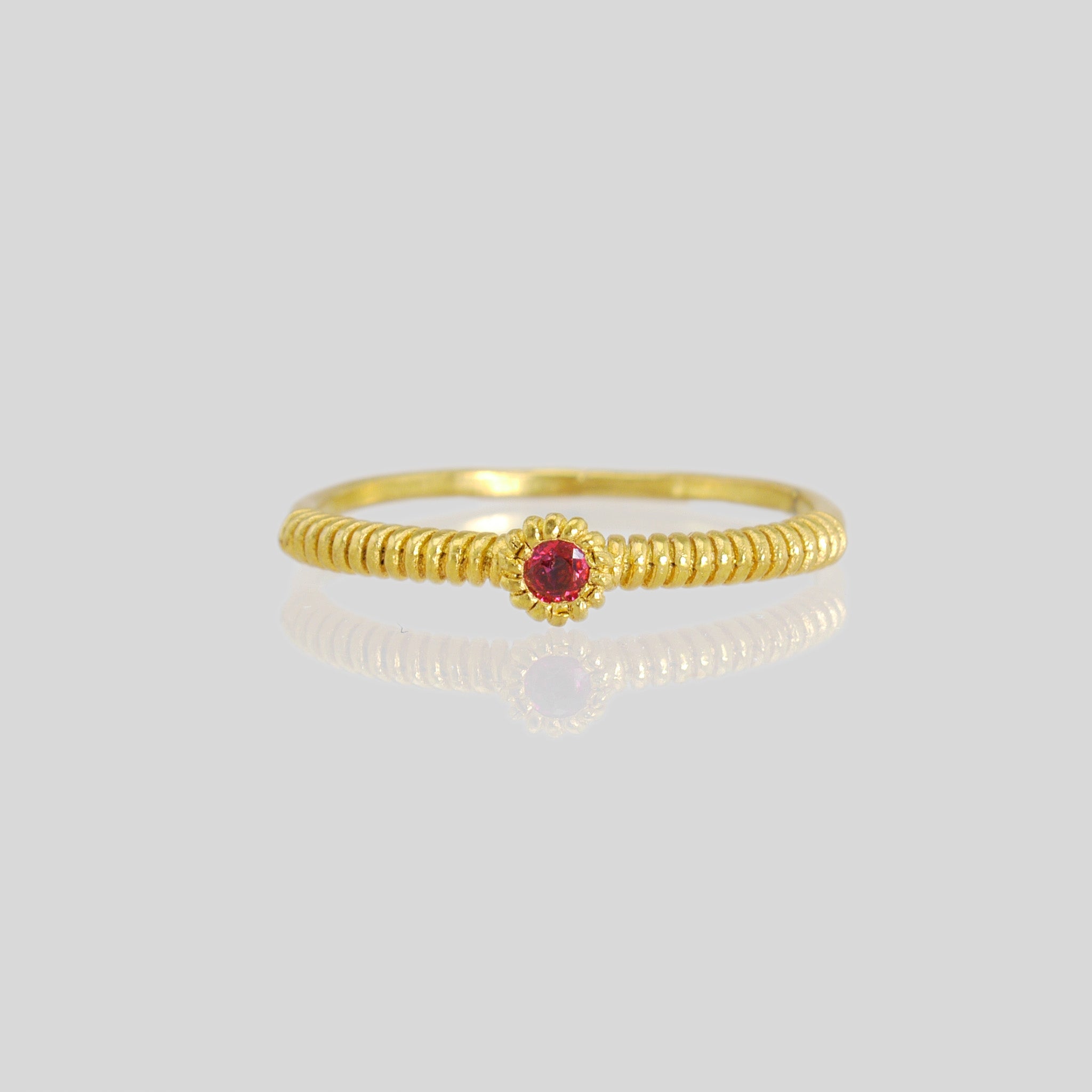 Front view of a thin gold ring with a coiled gold string, showcasing a vivid Ruby at its center. Elegant and charming, it radiates subtle allure.