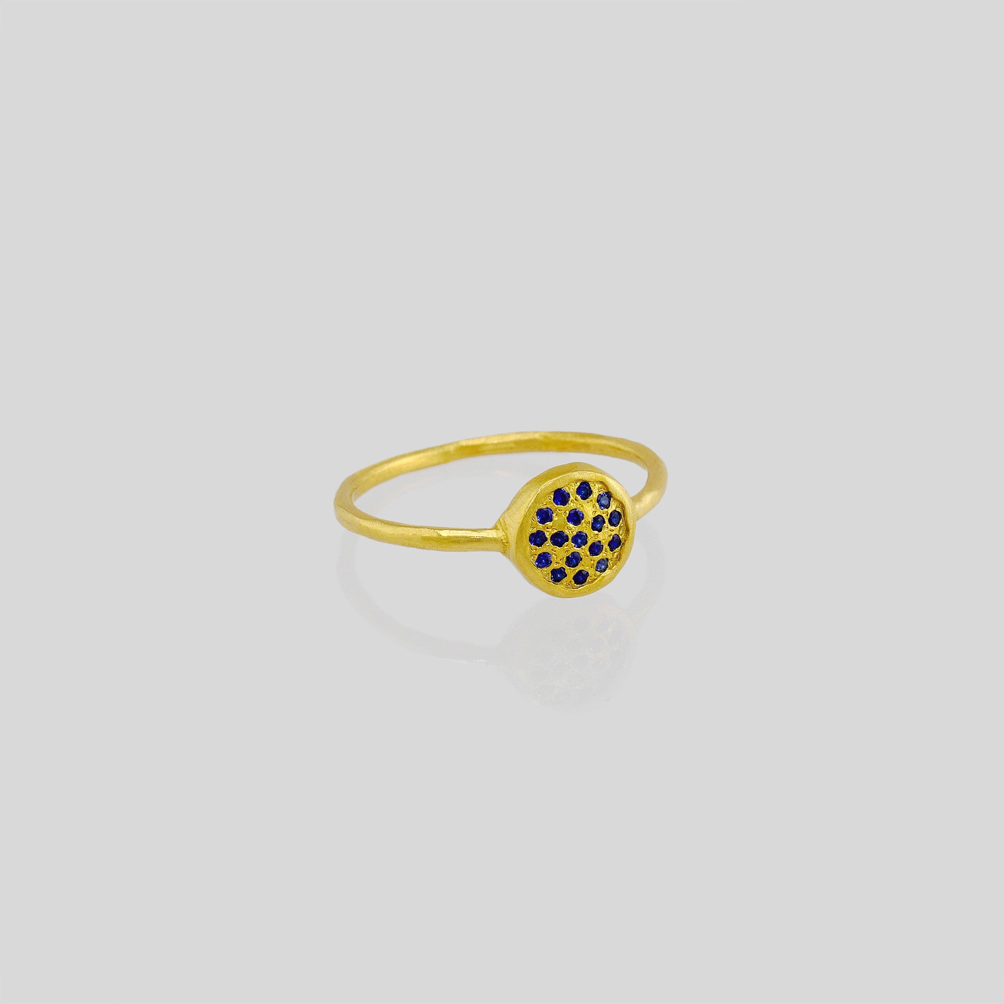 Delicate hand-made gold ring with a circular plate set with tiny Sapphires. The sparkle from the stones resembles a starry night. 