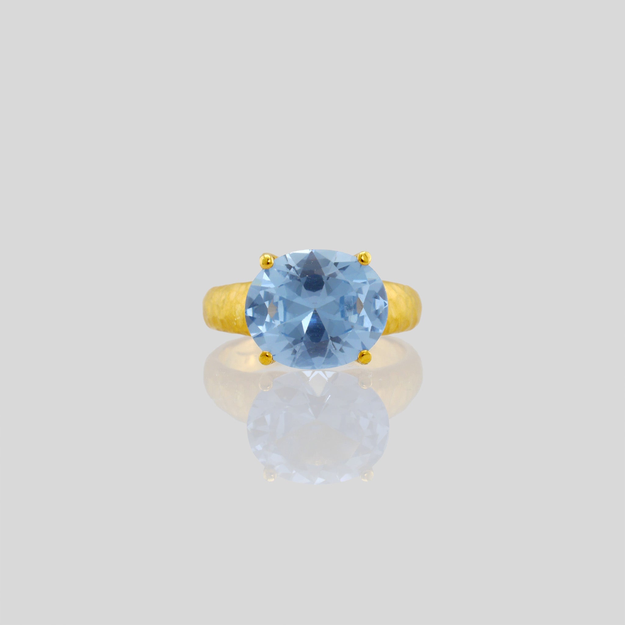 Front view of 18k Gold ring featuring four stems holding an elliptic Blue Topaz, combining rich color depth with a dignified presence.
