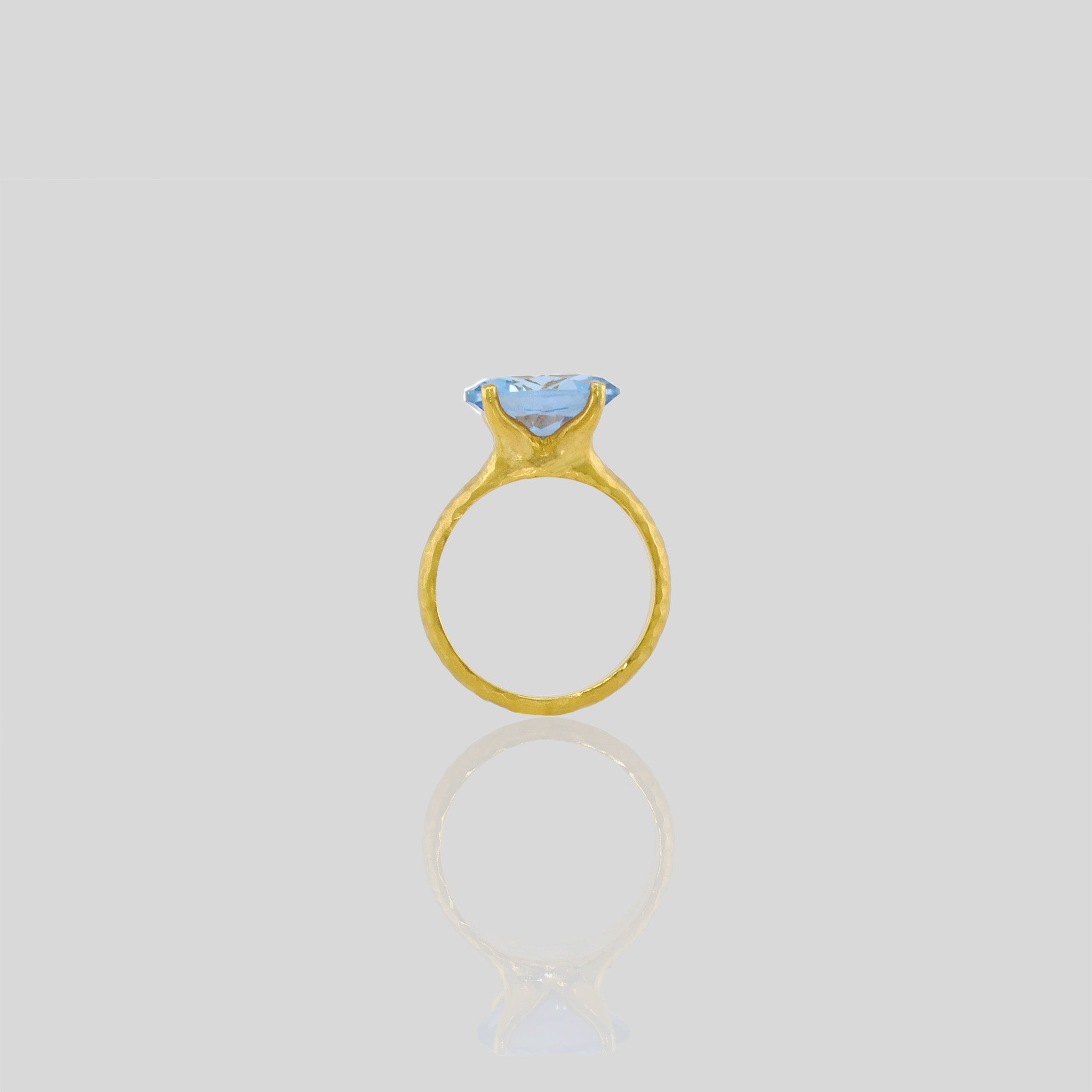 18k Gold ring featuring four stems holding an elliptic Blue Topaz, combining rich color depth with a dignified presence.
