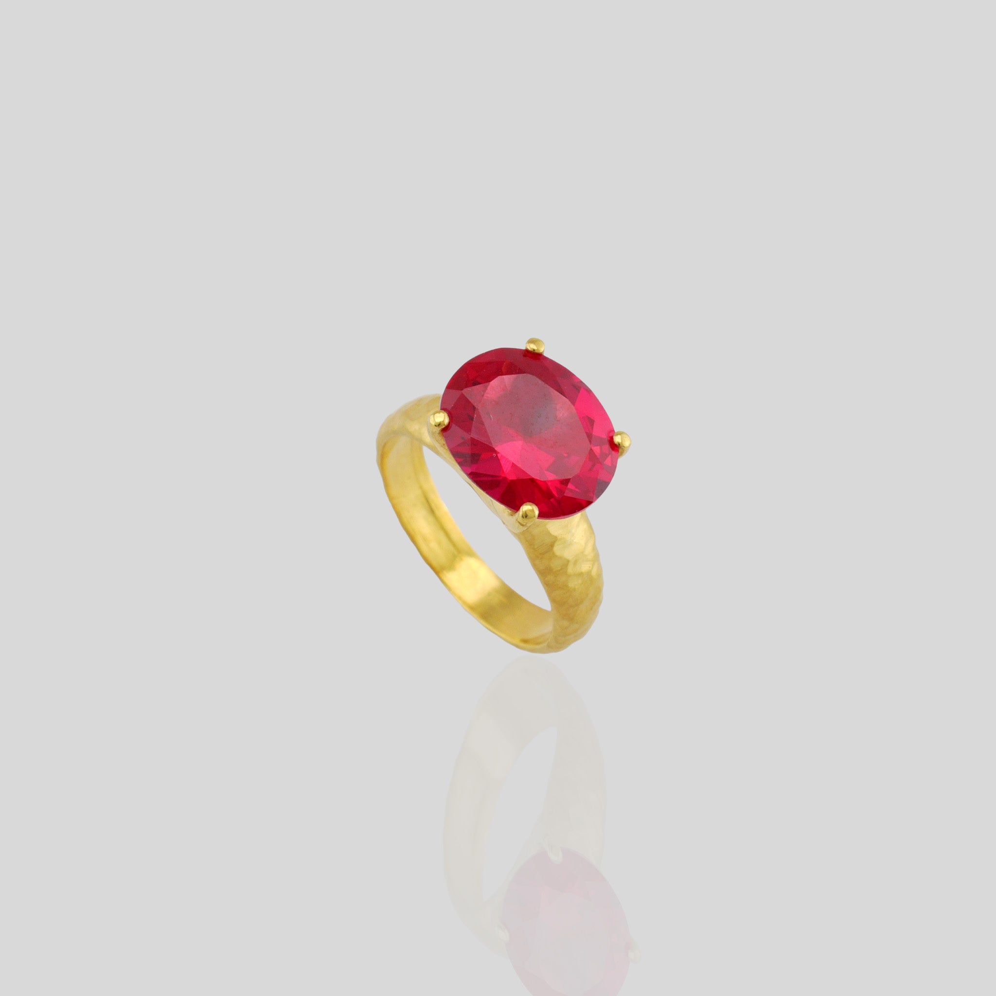 Top view of 18k Gold ring featuring four stems holding an elliptic Ruby, combining rich color depth with a dignified presence.