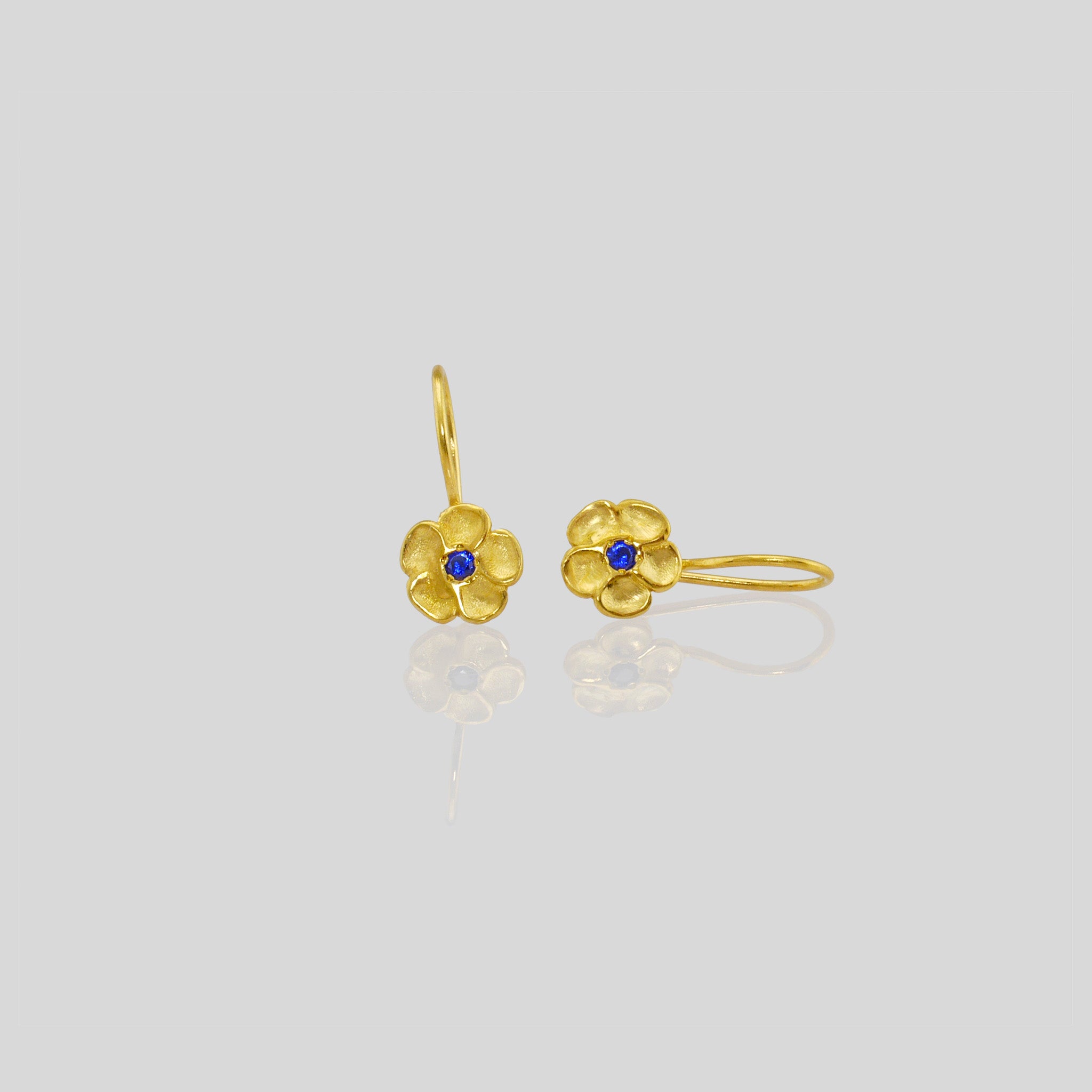 Delicate yellow gold flower drop earrings with a sparkling Sapphire center. Perfect for any occasion!