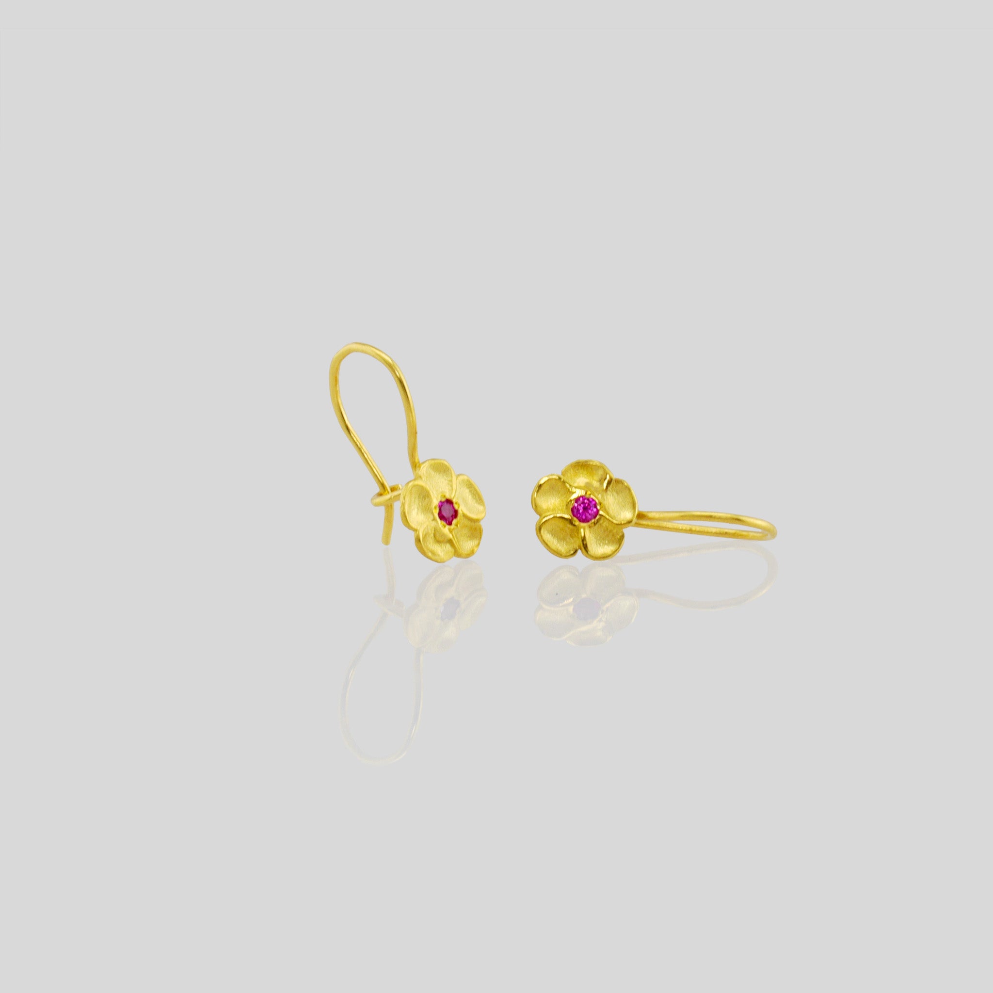 Front and side view of delicate yellow gold flower drop earrings with a sparkling ruby center. Perfect for any occasion!
