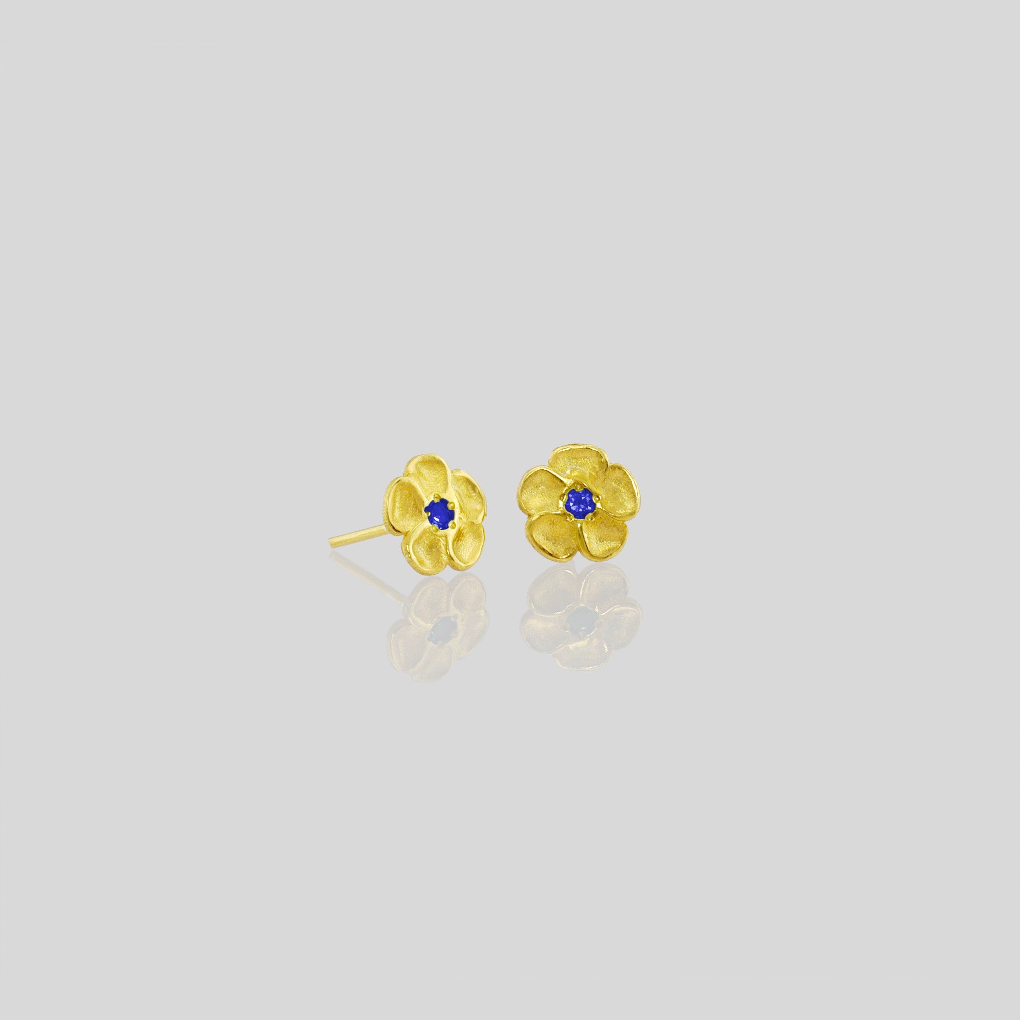 Delicate yellow gold flower stud earrings with a sparkling Sapphire center. Perfect for any occasion!
