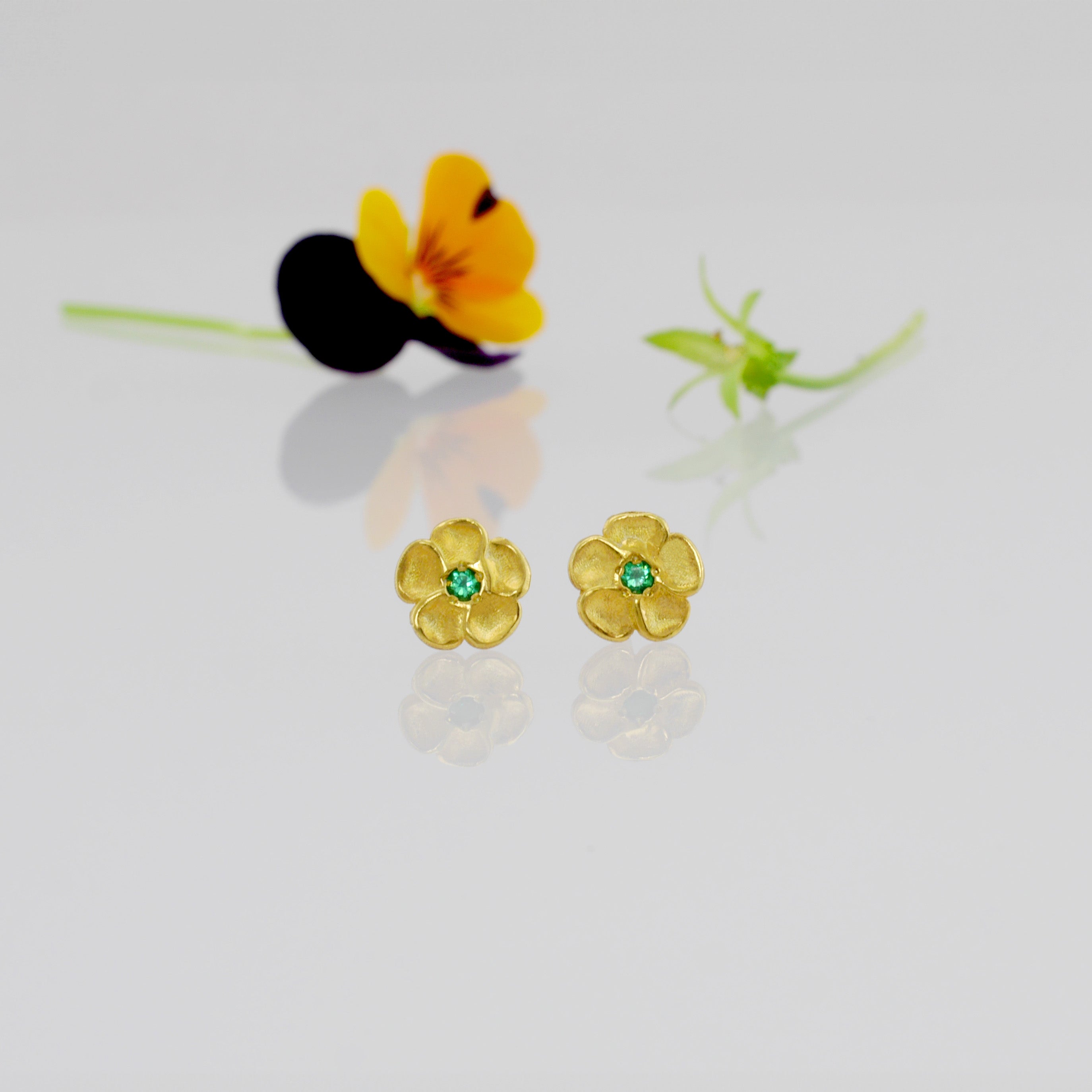 Delicate yellow gold flower stud earrings with a sparkling Emerald center. Perfect for any occasion!