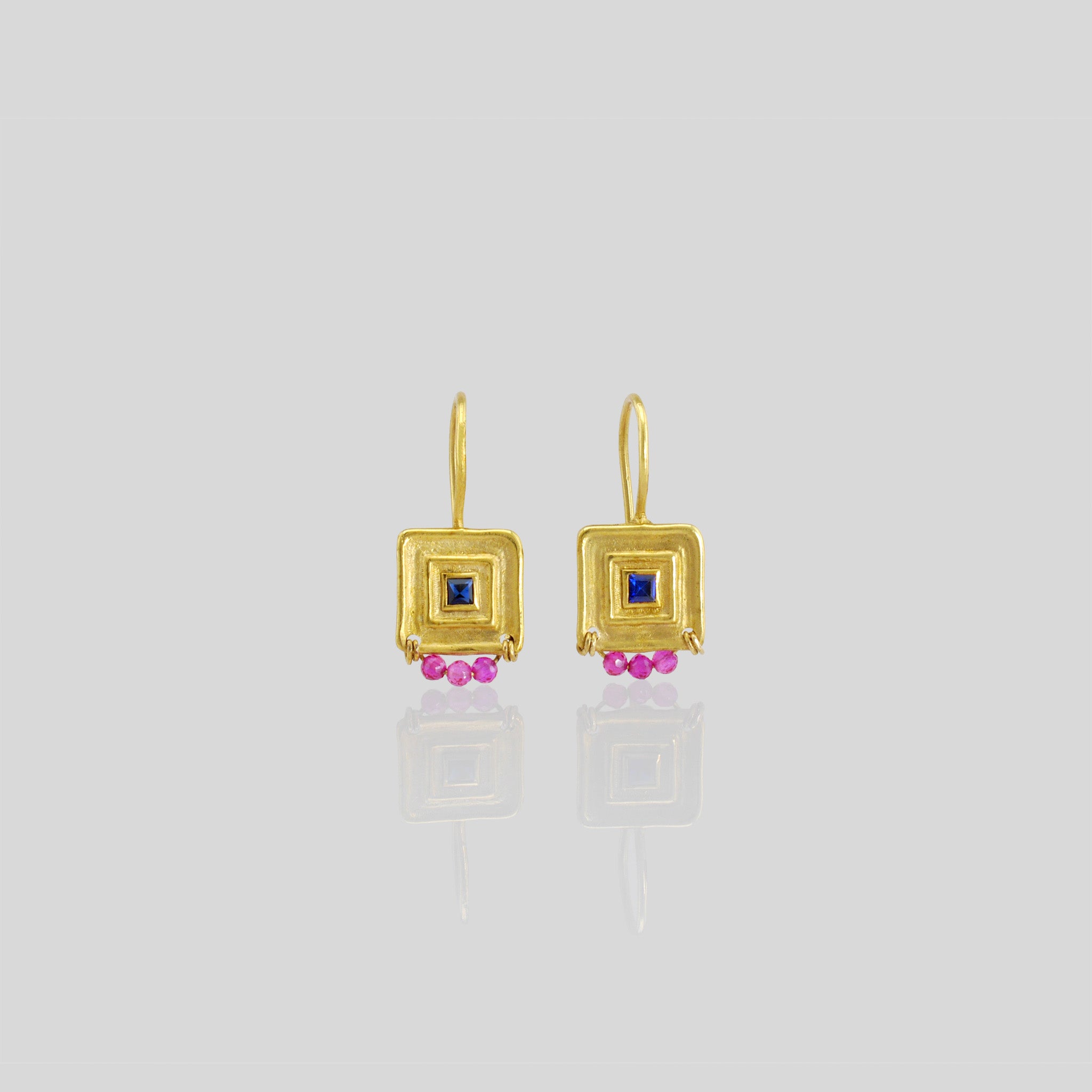 Unique gold square drop earrings featuring a square sapphire gemstone framed by a line pattern, with three hand-woven ruby beads at the bottom for an elegant Egyptian vibe.