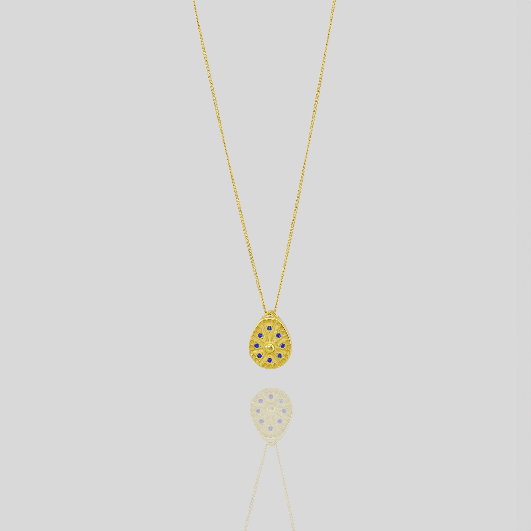 18k Gold pendant resembling a Sundial clock, accented with small Sapphires between the edges of each clock hand. A luxurious and timeless addition to any collection.