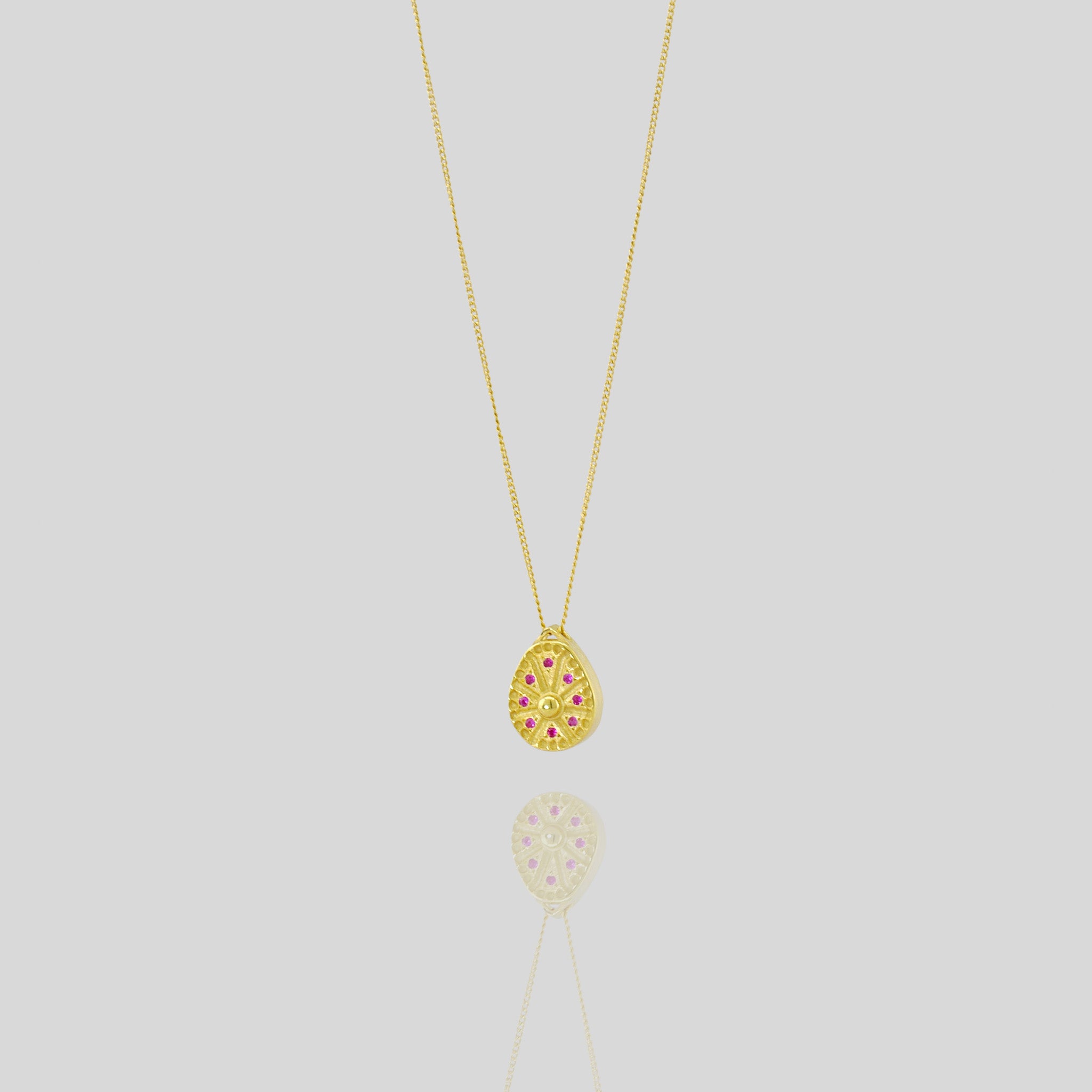 18k Gold pendant resembling a Sundial clock, accented with small Rubies between the edges of each clock hand. A luxurious and timeless addition to any collection.