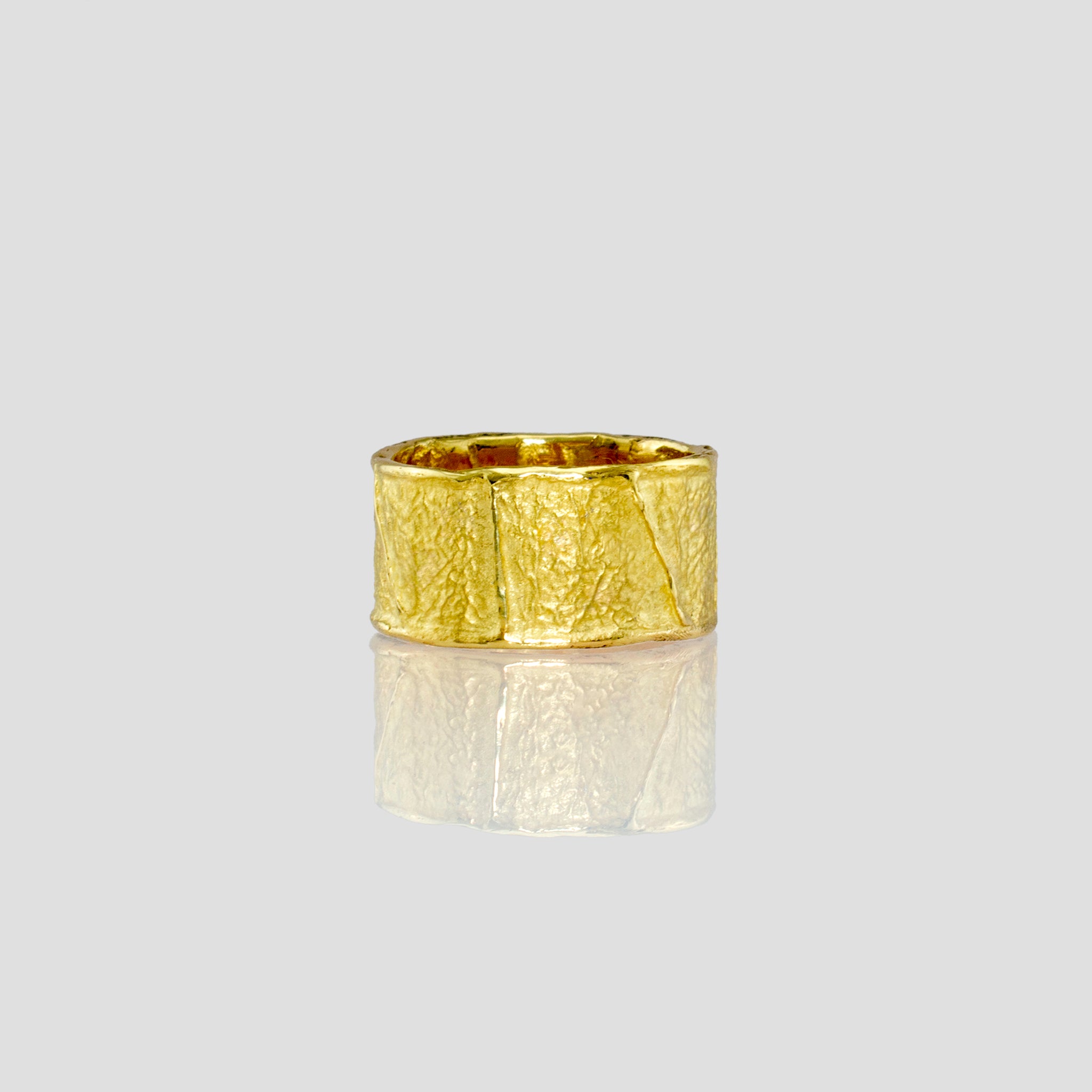 A beautifully crafted 18k Yellow Gold Ring with an innovative wrinkled texture, drawing inspiration from ancient Egyptian elegance, showcased in a sleek and sophisticated style without diamonds.