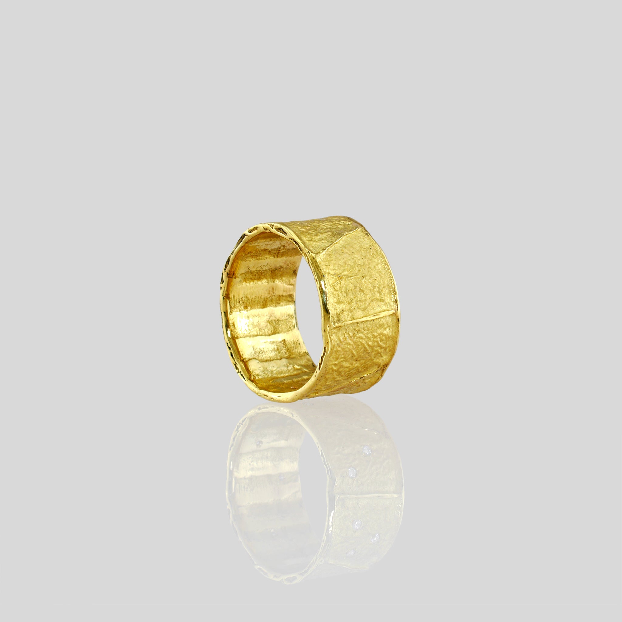 A beautifully crafted 18k Yellow Gold Ring with an innovative wrinkled texture, drawing inspiration from ancient Egyptian elegance, showcased in a sleek and sophisticated style without diamonds.