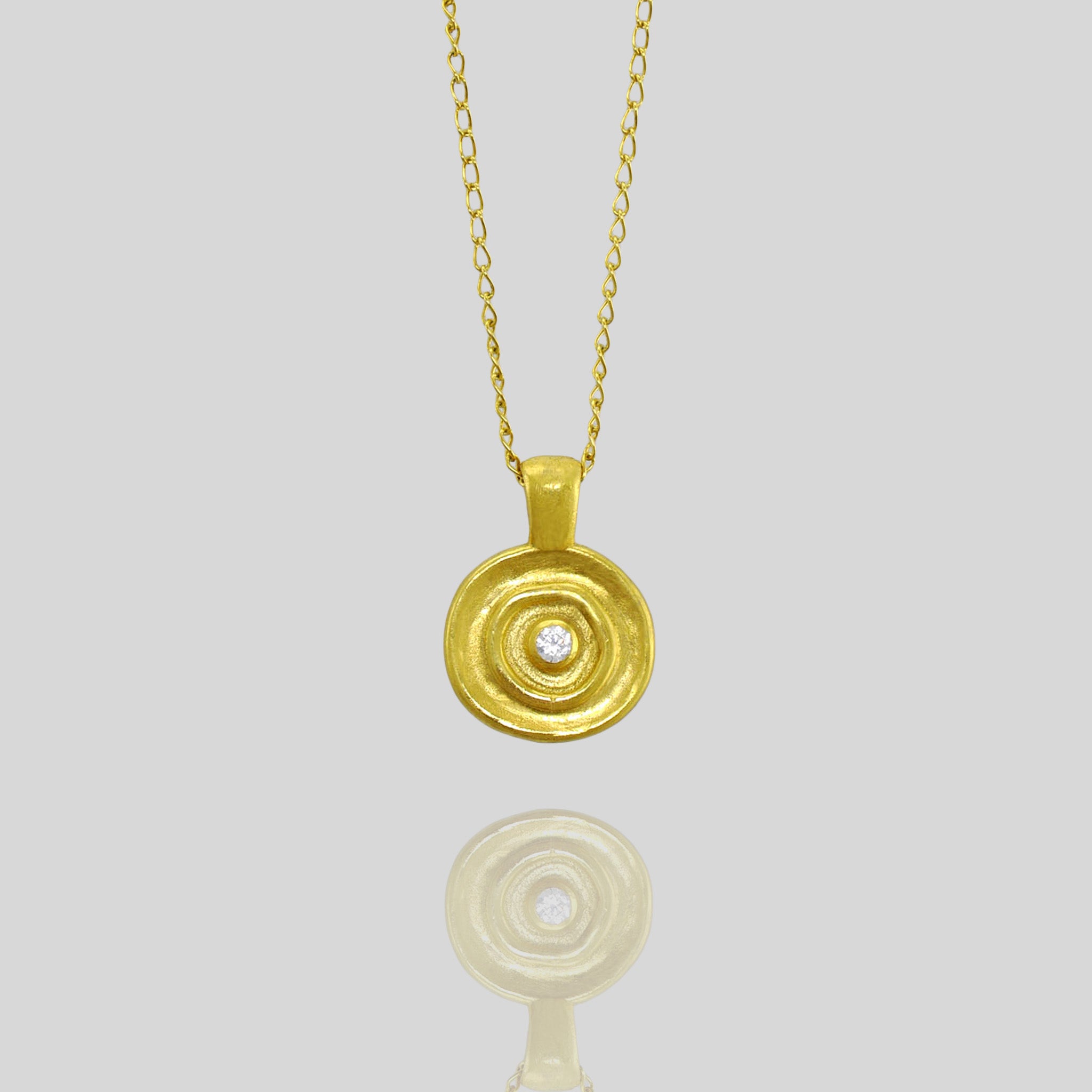 Close up of Handcrafted Yellow Gold round pendant, featuring a central diamond inspired by ancient Egyptian Pharaohs' jewelry.