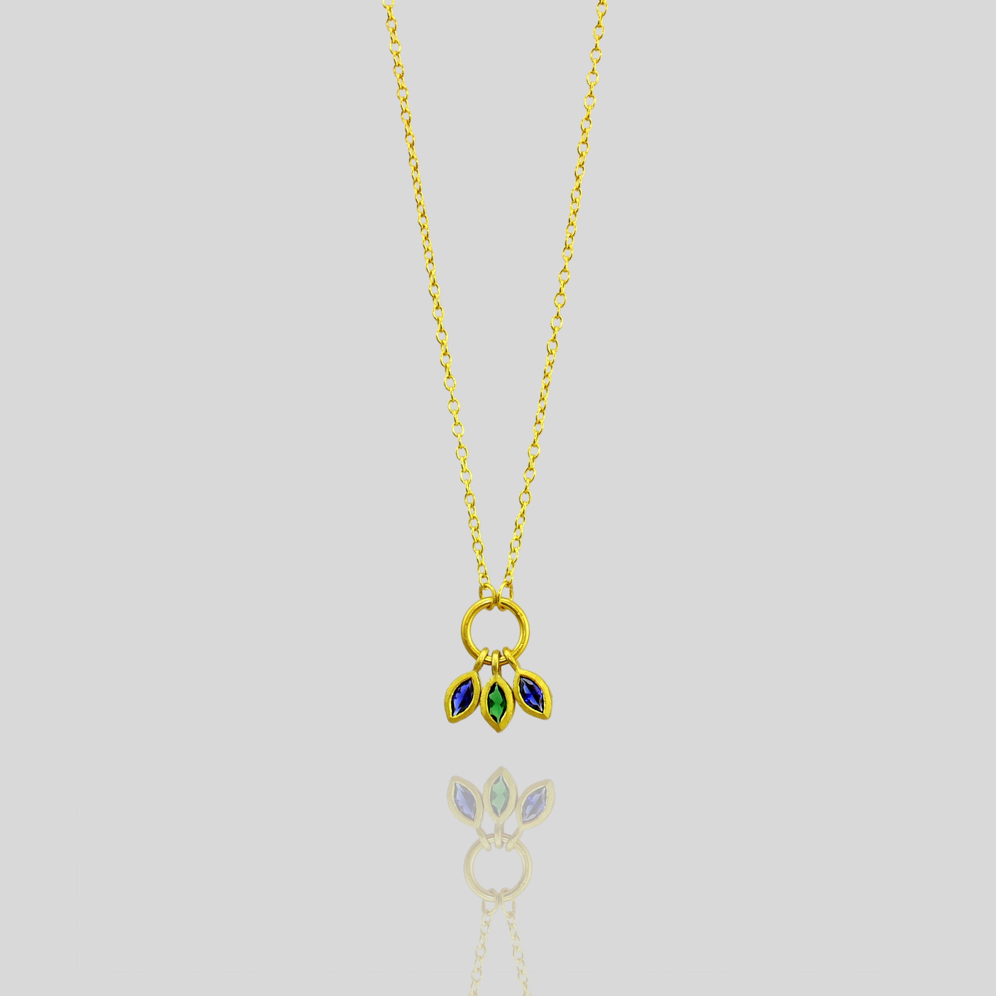 18k Gold Marquee pendant with three precisely cut gemstones, an emerald and two sapphires, combining to offer a vibrant mix of color and elegance.