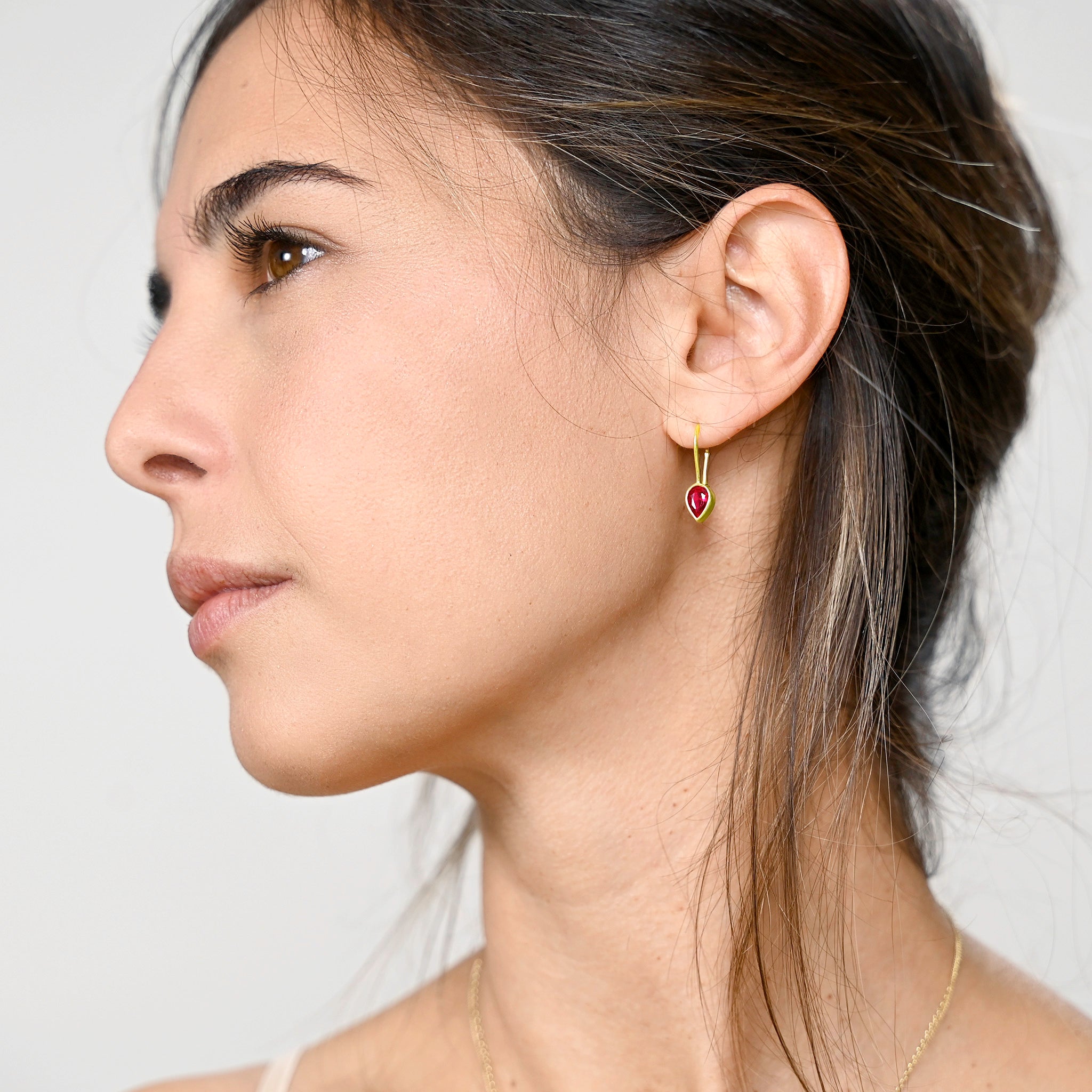 Model elegantly displaying gold drop earrings with a radiant drop-shaped Ruby, enhancing spiritual harmony and adding a touch of sophistication to any attire.