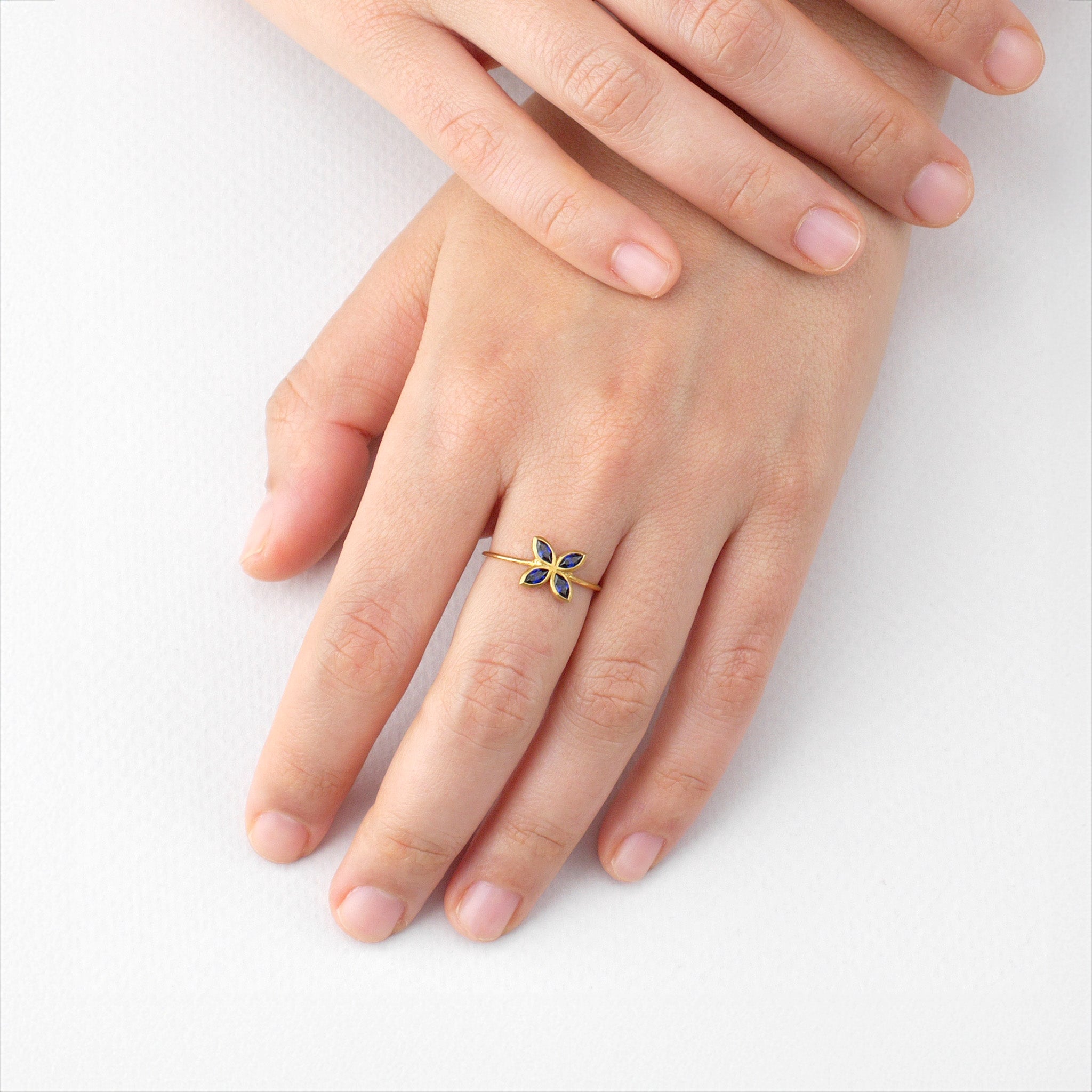 Model wearing the delicate sapphire Marquee Gold ring, its flower-shaped design and radiant color making it a stunning and cheerful accessory for any outfit.